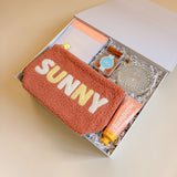 Summer-themed happy hour gift box with cozy SUNNY pouch and peach-inspired self-care gifts