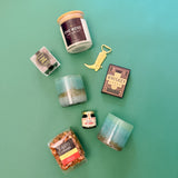 Flat lay of Desert Nights gift box contents including artisan whiskey glasses, western candle, gourmet snacks, hot honey, poker cards, and cowboy boot bottle opener.