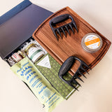 Gather & Graze gourmet gift box featuring a wooden serving board, artisan snacks, salami, hot honey, steakhouse seasoning, and charcuterie accessories.