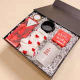 Be Mine Valentine’s luxury care package gift box including heart socks, soy candle, bath bomb, ring tray, red wine chocolate, and love you more mug.