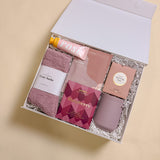 Luxury Wine Down gift box featuring gourmet raspberry chocolate, rose candy gummies, champagne-scented lotion, cozy orchid socks, and insulated wine tumbler.