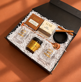 Holiday cocktail gift featuring two rocks glasses, a copper bar spoon, cinnamon sticks and sweet-and-salty snacks