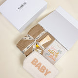 Confete branded gift box lid beside the Mommy + Me gift set for expecting moms.