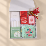 Colorful holiday gift box for her featuring self-care treats, chocolate, a notebook, festive frame, and fuzzy Oh What Fun pouch.