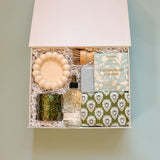 Flat lay of modern housewarming gift box with cozy home gifts and neutral decor items
