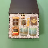 Overhead view of Desert Nights gift box with western-inspired gifts including whiskey glasses, candle, bourbon pecans, hot honey, gourmet popcorn, and playing cards.
