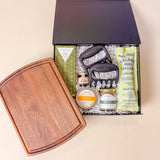 Open Gather & Graze gift box showcasing gourmet snacks, charcuterie essentials, serving board, hot honey, seasoning, and artisan chocolate.
