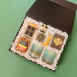 Desert Nights luxury western gift box featuring artisan whiskey glasses, The West candle, gourmet snacks, hot honey, poker cards, and a cowboy boot bottle opener.
