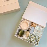 Cozy housewarming gift box with towel, artisan chocolate, soap, and home accessories