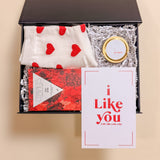 Luxury mini Valentine’s gift box including heart socks, Be Mine soy candle, and red wine chocolate bar.