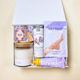 Calm lavender self-care gift box with candle, herbal tea, hand cream, moisturizing socks, matches, and Something Sweet truffles. 