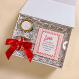 LOVE Valentine’s Day gift box with acrylic scalloped picture frame, 2oz Be Mine soy candle, and Maeve bubbly bon bons with red bow.