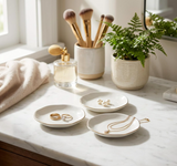 White porcelain ceramic ring dish holding rings and small jewelry on a vanity.