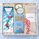 Après ski holiday gift box with hot chocolate, cozy socks, a wood-wick candle, chocolate and candy canes