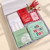 Oh What Fun holiday self-care gift with a sea berry bath bomb, Chill Mode eye gels, gourmet chocolate, notebook, and photo frame.
