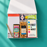Open Game Night gift box with First to Worst party game, caramel popcorn, chocolate, hand cream, candy, Chaos Coordinator notepad and gold pen.