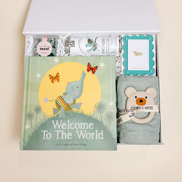Confete New Baby Gift Box with swaddle, welcome book, pregnancy tea, teether, and chocolates arranged in a white keepsake box.
